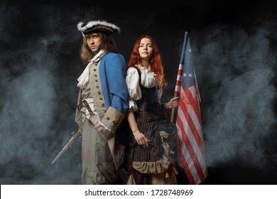 Man in form of officer of United States War of Independence and girl in historical dress of 18th century. July 4 is US Independence Day. Studio photo on black background