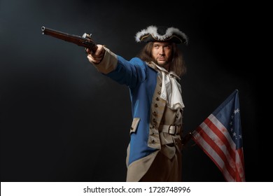 Man In Form Of Officer Of United States Revolutionary War With A Flag And Gun. July 4th, Independence Day USA Concept. Studio Photo On Black Background