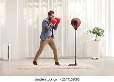 Man In Formal Clothes Punching A Free Standing Boxing Bag At Home