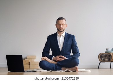 A Man In A Formal Suit Meditates While Sitting In A Fitness Room With A Laptop.