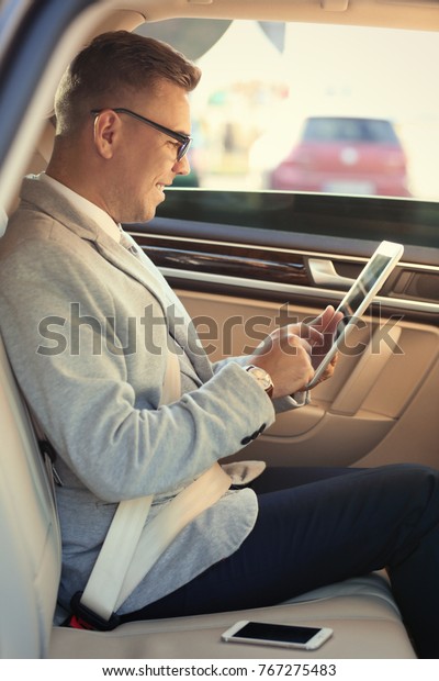 Man in formal\
wear with tablet computer in\
car