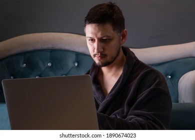 Man Freelancer In A Dressing Gown Working From Home On A Laptop