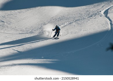 Man freerider with ski quickly slides down a mountain slope covered powdery snow. Freeride skiing concept