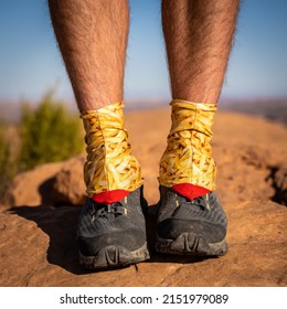 Man With French Fry Pattern Hiking Gaiters Over Shoes Standing On Rock