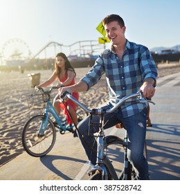 Man With Friends Riding Bikes On Bike Path At Santa Monica Beach