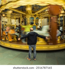 the man in front of the carousel, slow shutter speed, motion blur