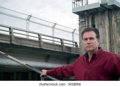 Man in front of a concrete structure day dreaming or with an expression on his face as if deep in thought.