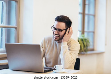Man in front of laptop computer with headset - Shutterstock ID 1335945023