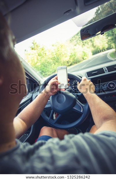 A man in the front seat of his car\
is photographing the road in front of him with his\
phone