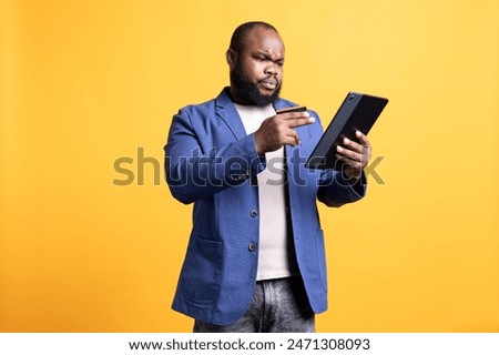 Man with frown on face while adding payment method on website, seeing insufficient funds error, studio background. Upset person getting transaction rejected, wrongly typing credit card data on tablet
