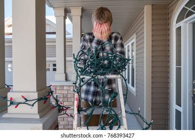 Man frustrated on a ladder while hanging tangled holiday lights.