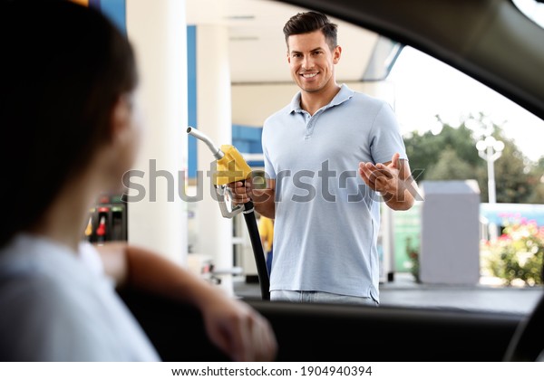 Man with fuel pump nozzle talking to his\
girlfriend at self service gas\
station
