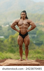 A man with full of abs post in the forest