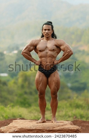 A man with full of abs post in the forest
