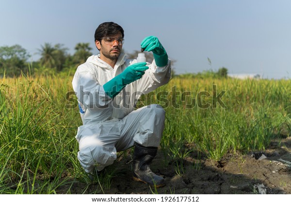 A man in full body protective suit collecting\
samples of soil