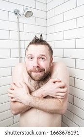Man with a funny facial expression is shocked by taking a cold shower, he froze, covers body with hands and looks at the camera.