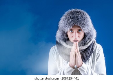 A Man In A Fur Hat And Scarf Warms His Hands With His Mouth. Cold Weather. Bask. It's Winter Time. Isolate