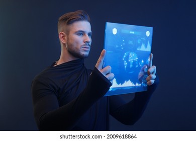 Man with futuristic tablet in hand. Guy using VR glasses. Augmented reality, future technology concept. Blue neon light. Futuristic holographic interface to display data.
