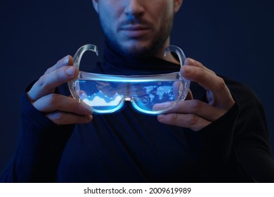 Man with futuristic tablet in hand. Guy using VR glasses. Augmented reality, future technology concept. Blue neon light. Futuristic holographic interface to display data.