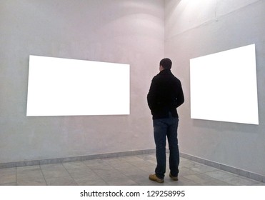 Man in gallery room looking at empty frames