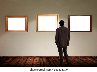 Man in gallery room looking at empty picture frames