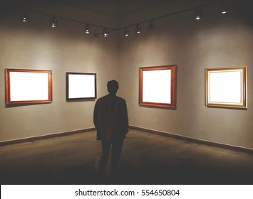 Man In Gallery Room Looking At Empty Picture Frames - Mock Up Art Concept