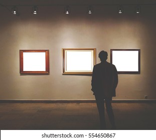 Man In Gallery Room Looking At Empty Picture Frames - Mock Up Art Concept