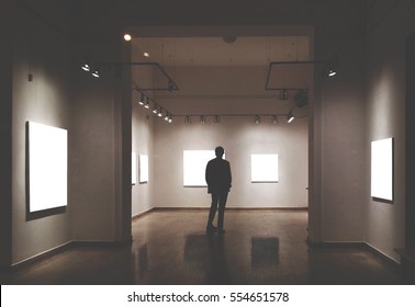 Man In Gallery Room Looking At Empty Picture Frames - Mock Up Art Concept