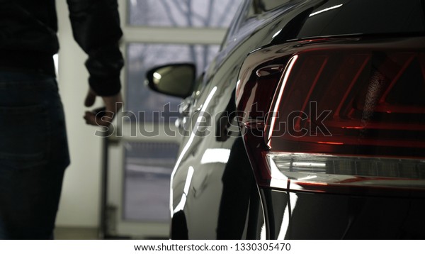 A man in the\
garage (car service) Checks the car alarm and then goes off (comes\
in) turning off (turning on) the lights behind him. Concept of:\
Auto garage, Security.	\
