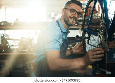 Man, garage and confident as bicycle mechanic with lens flare in startup or small business. Workshop, portrait and smile or happy as handyman with fixing bike at repair or maintenance shop and proud - Powered by Shutterstock