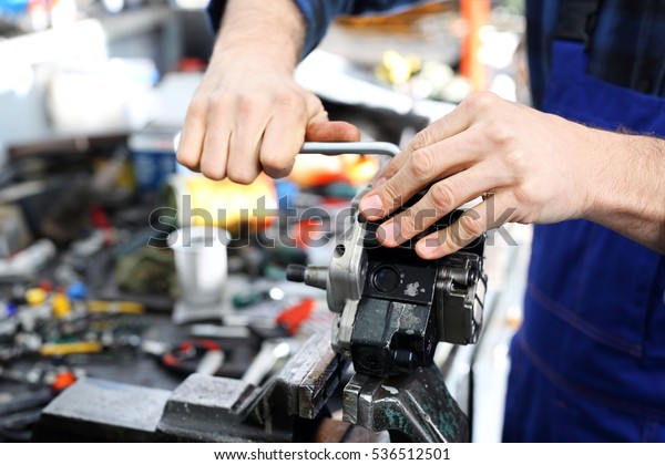 The man in the garage with a wire brush cleans
mechanical parts 