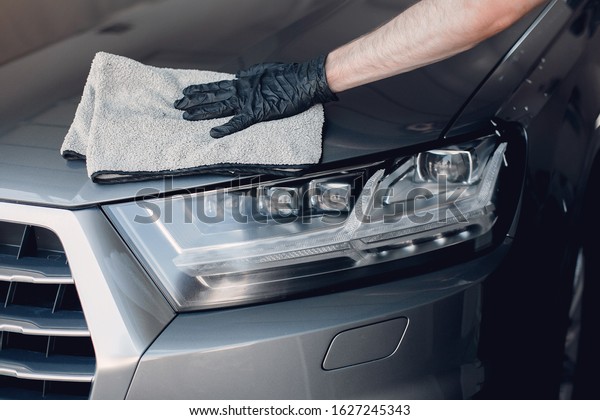 Man in a garage. Worker\
polish a car.