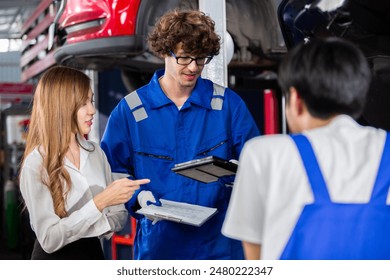 Man garage worker and woman customer talking to discuss details of car repairs. male mechanic holding clipboard and writes down repair list for female client. Transportation and car insurance concept - Powered by Shutterstock