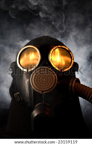 Man in gas mask with fire reflection in the eyes over smoky background