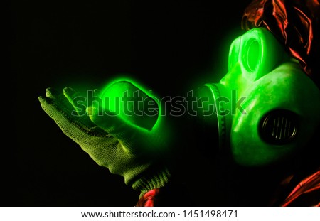 Man in the gas mask holding radioactive luminous apple. Radiation influence. Environmental pollution. Chernobyl concept. Dangerous nuclear power.