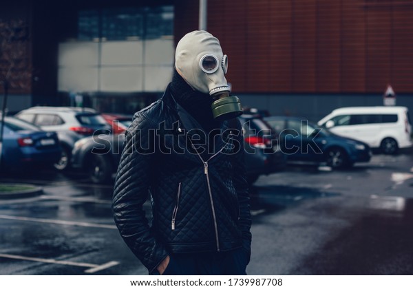 man in a gas\
mask standing in a city Parking\
lot