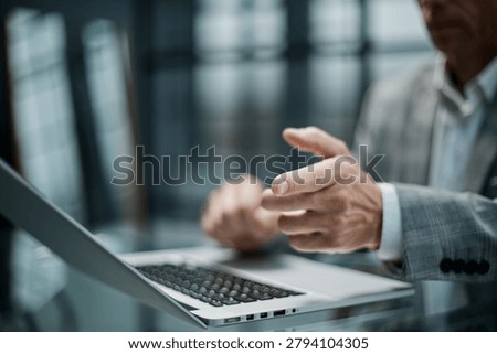 Man gestures thoughtfully while working on laptop