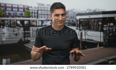 Man gesturing hands out palms down on street by canal boat in amsterdam; confidence casual friendliness.