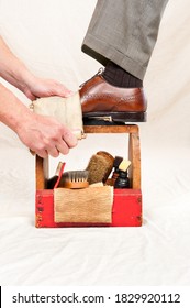 A Man Gets His Shoes Polished By A Worker Using A Vintage Shoe Shine Box With Camel Hair Brushes, Polishing Rag, Polish And A Wooden Shoe Platform.