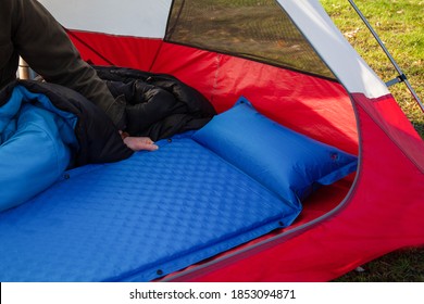 A Man Gets His Tent And Sleeping Bag Ready At A Campground By Inflating And Setting Up His Blue Blow-up Mattress Pad To Put For Under His Sleeping Bag