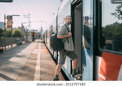 A man gets on a train on the platform. A young guy, a passenger with a backpack, enters the carriage from a high platform in the city on a sunny day