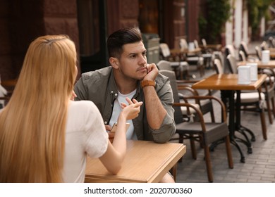 Man getting bored during first date with overtalkative young woman at outdoor cafe - Shutterstock ID 2020700360