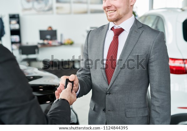 Man getting\
car key from car seller in auto\
salon