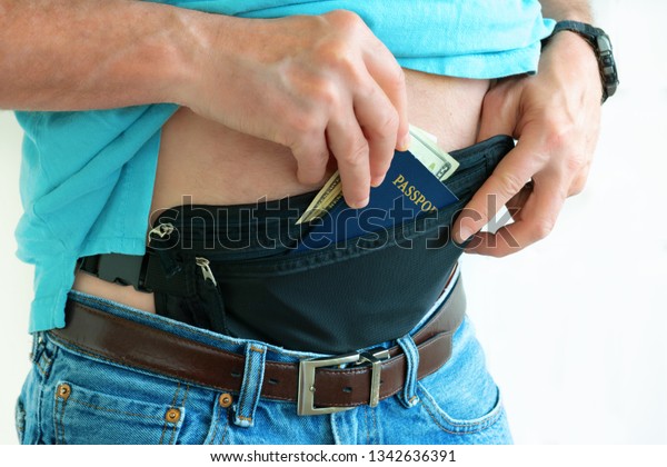 Man getting cash and passport from hidden travel
money belt that he has under his clothes to protect himself from
pickpockets and credit card scanners safely transporting documents
in transit.