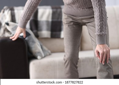 Man Getting Up From Couch And Holding On To Sore Knee Closeup. Arthritis Treatment Concept