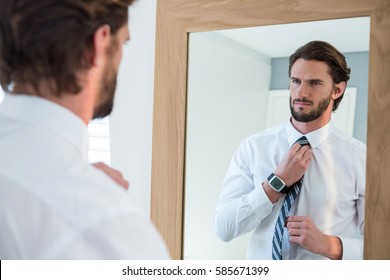 Man Getting Dressed In Bedroom While Looking At Mirror At Home