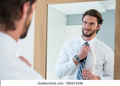 Man Getting Dressed In Bedroom While Looking At Mirror At Home