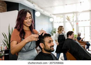 Mann bekommt einen Haarschnitt aus einer Friseurstyliste in einem Friseursalon