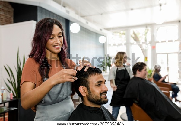 Man getting a haircut from a hair stylist at a\
barber shop