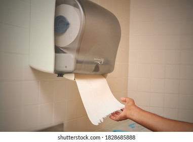 A Man Getting Issue Paper From An Automatic Wall Mounted Tissue Dispenser 